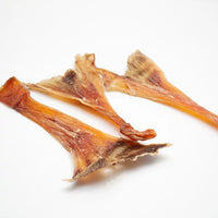 Three natural ostrich tendons dog chews side by side high protein low fat long lasting treat for teeth and gums.